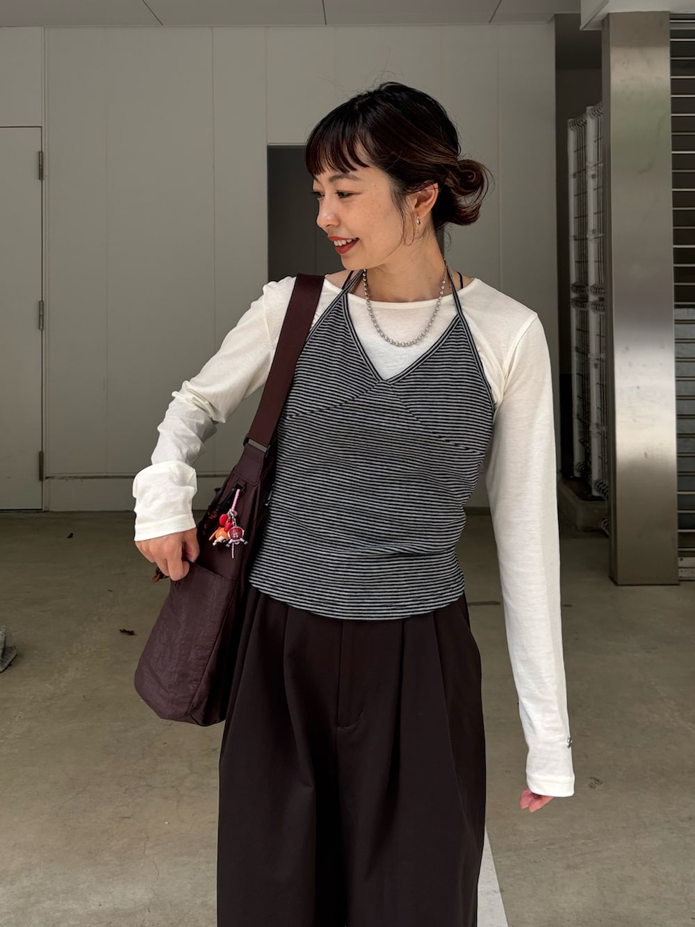 グレー系のキャミソール、ホワイト系のTシャツ/カットソー、ブラウン系のチノパンツを着用したレディースの秋コーディネートの4枚目の写真