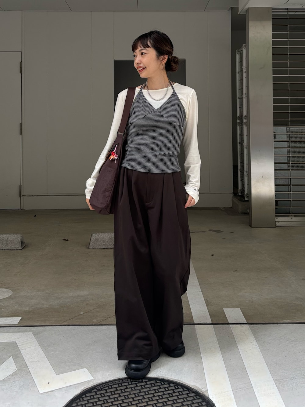 グレー系のキャミソール、ホワイト系のTシャツ/カットソー、ブラウン系のチノパンツを着用したレディースの秋コーディネートの2枚目の写真