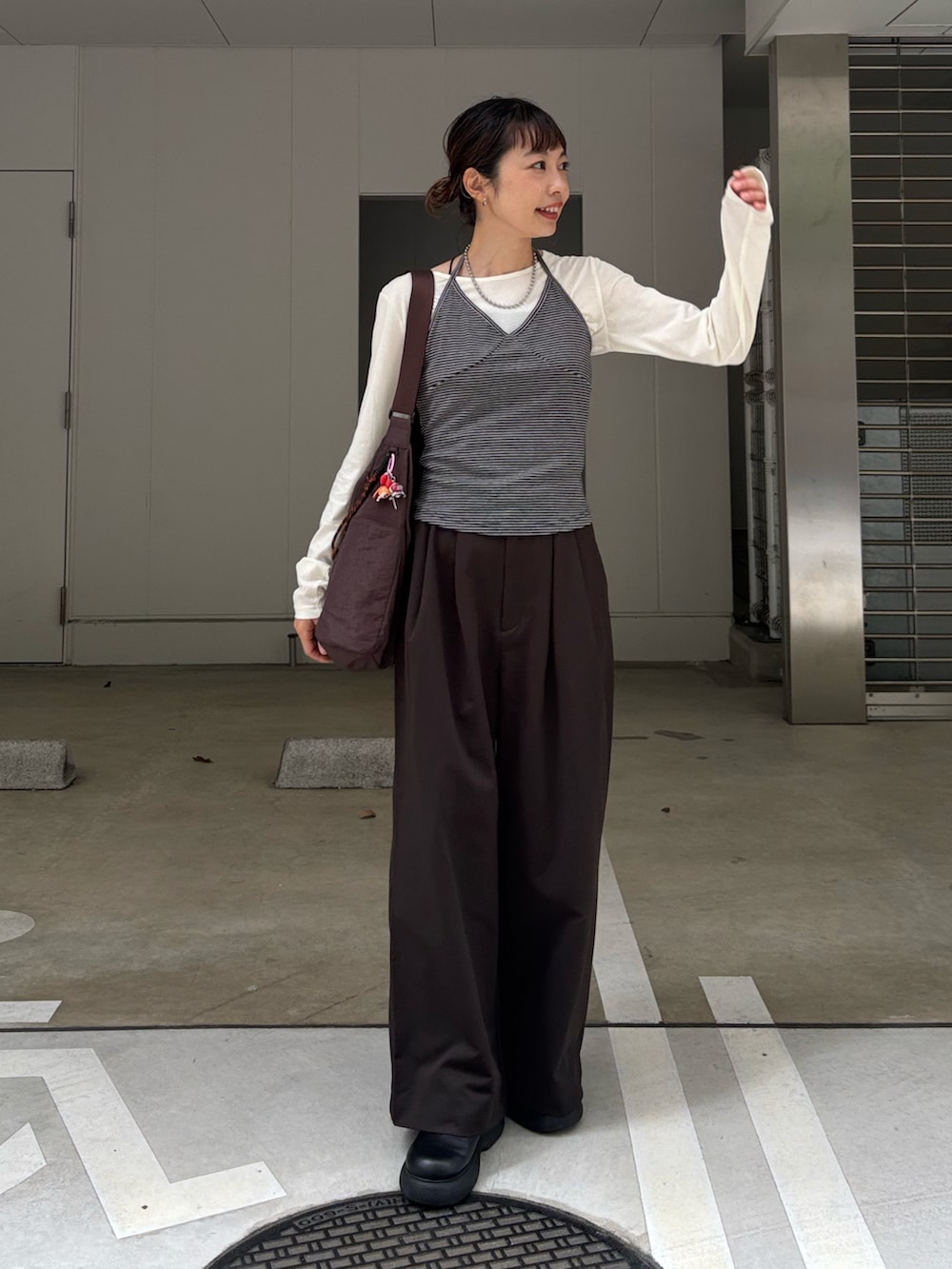 グレー系のキャミソール、ホワイト系のTシャツ/カットソー、ブラウン系のチノパンツを着用したレディースの秋コーディネートの3枚目の写真