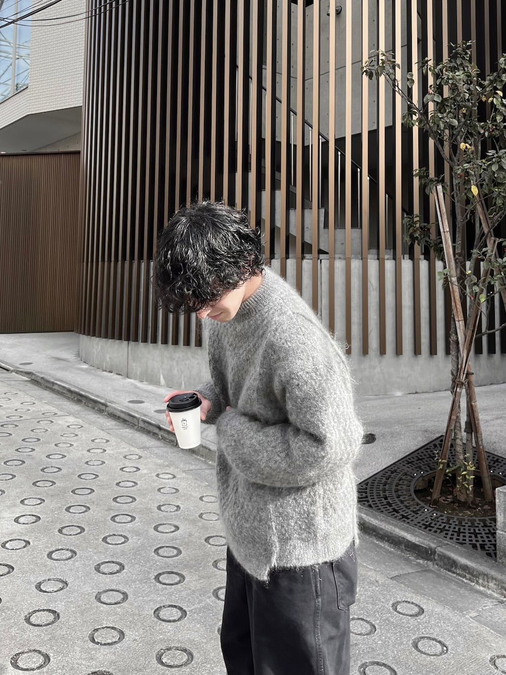 グレー系のニット/セーター、ブラック系のデニムパンツ、ホワイト系のスニーカーを着用したメンズの冬コーディネートの3枚目の写真