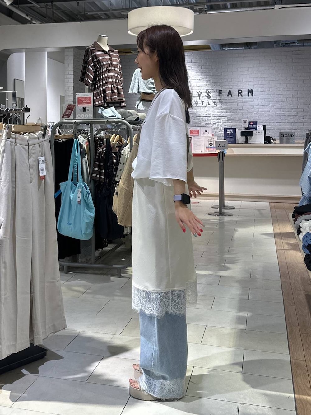 ベージュ系のショルダーバッグ、ホワイト系のTシャツ/カットソー、ブルー系のデニムパンツを着用したレディースの夏コーディネートの2枚目の写真