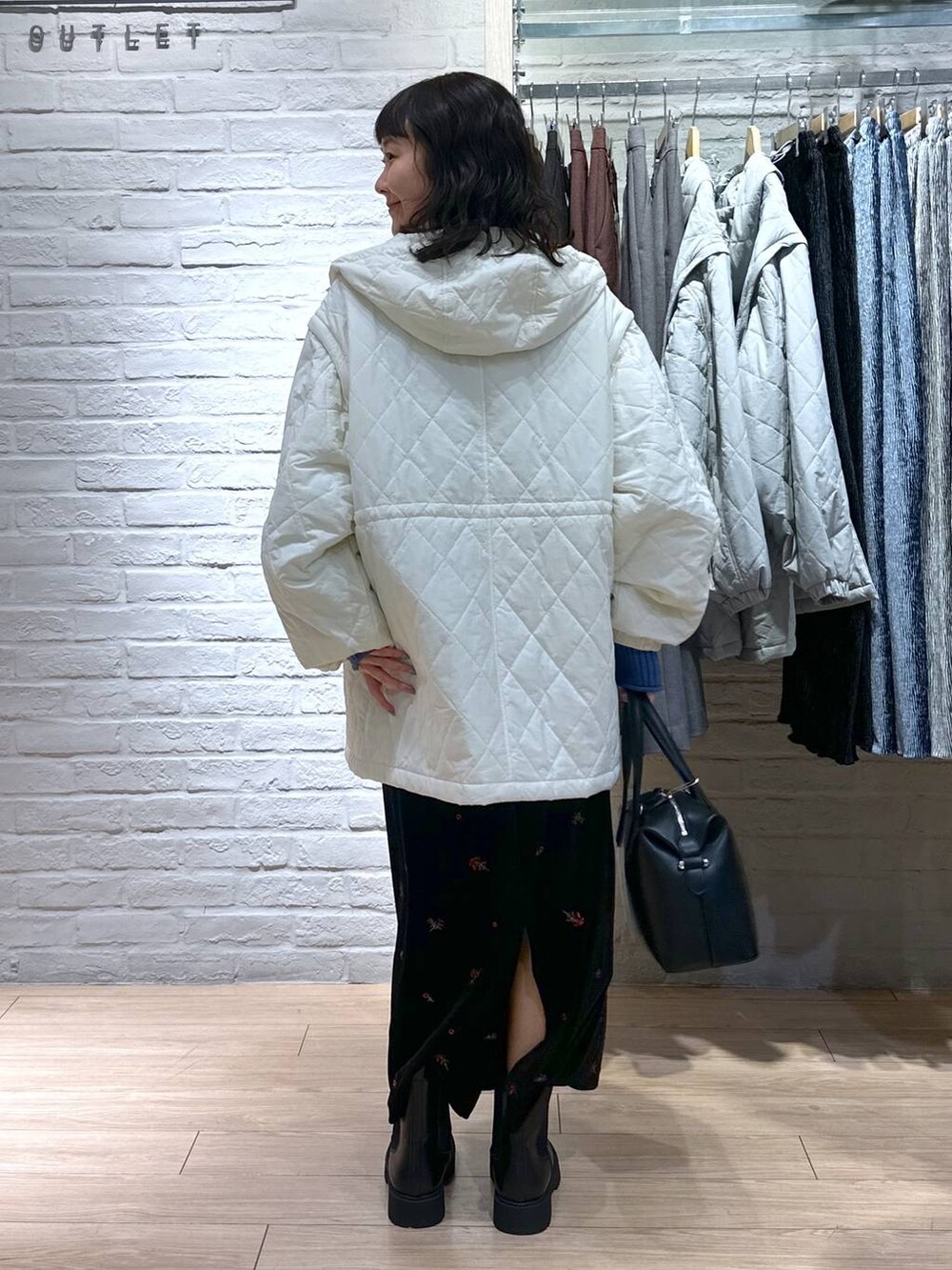 ブルー系のニット/セーター、ブラック系のブーツ、ホワイト系のブルゾンを着用したレディースの冬コーディネートの5枚目の写真