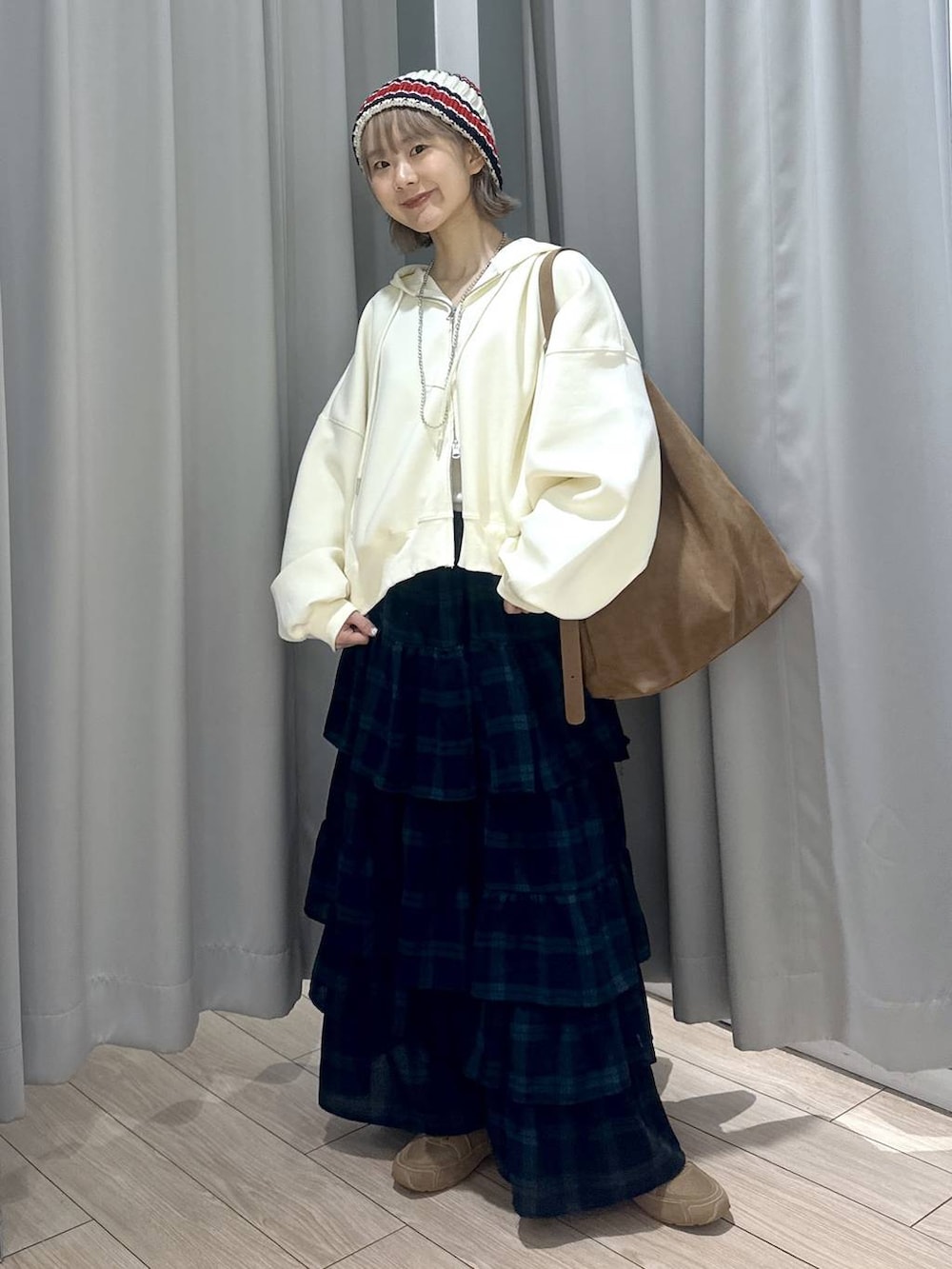 ベージュ系のショルダーバッグ、ブラウン系のスニーカー、グリーン系のスカートを着用したレディースの秋コーディネートの4枚目の写真