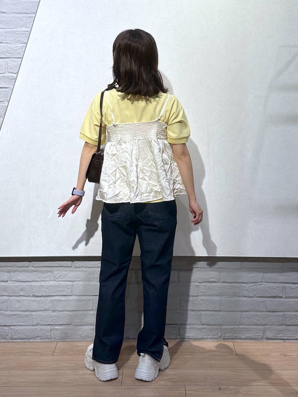 イエロー系のTシャツ/カットソー、ブラウン系のショルダーバッグ、ブルー系のデニムパンツを着用したレディースの秋コーディネートの4枚目の写真