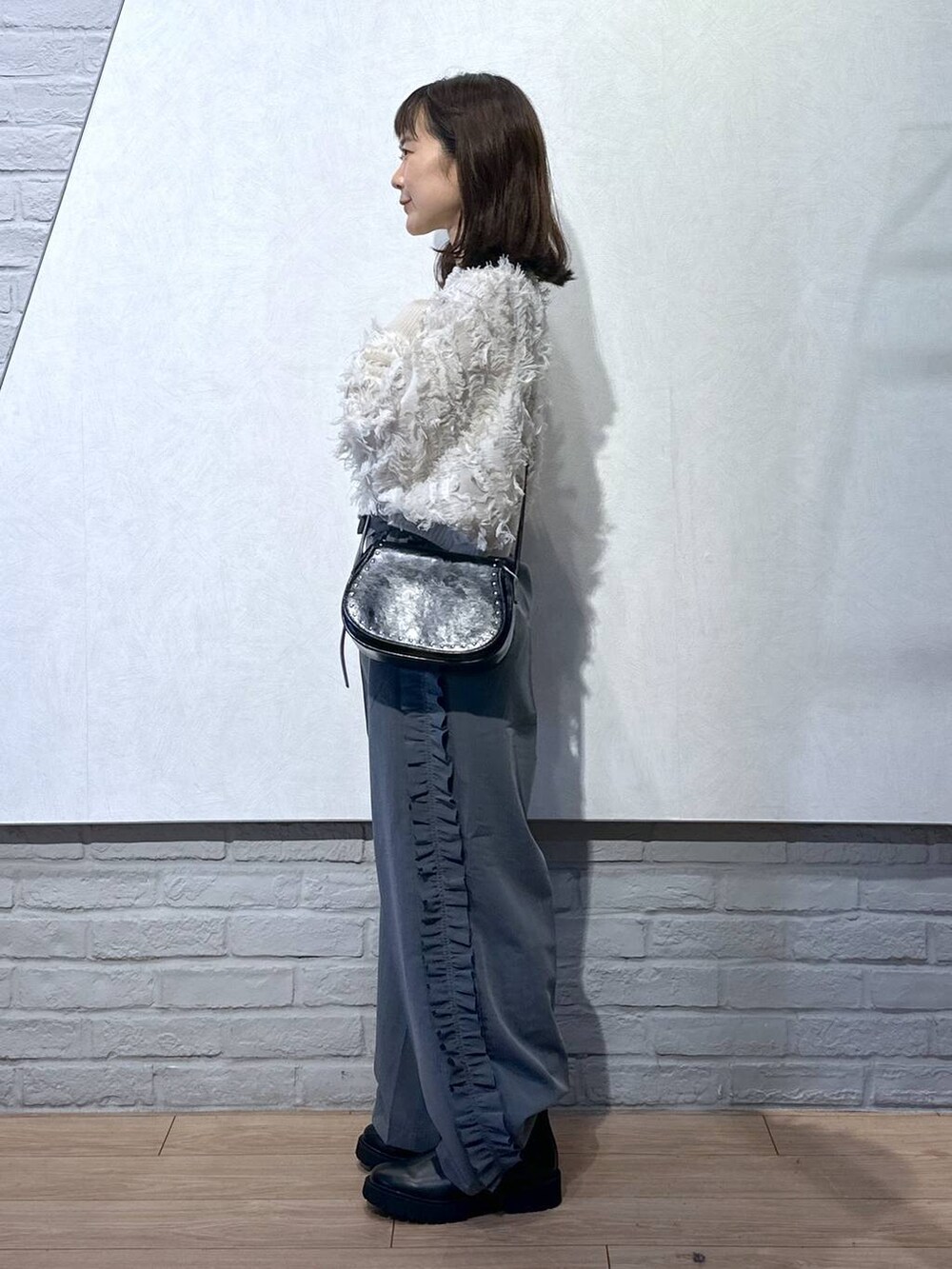 ブラック系のショルダーバッグ、ホワイト系のニット/セーター、ブラック系のブーツを着用したレディースの秋コーディネートの3枚目の写真