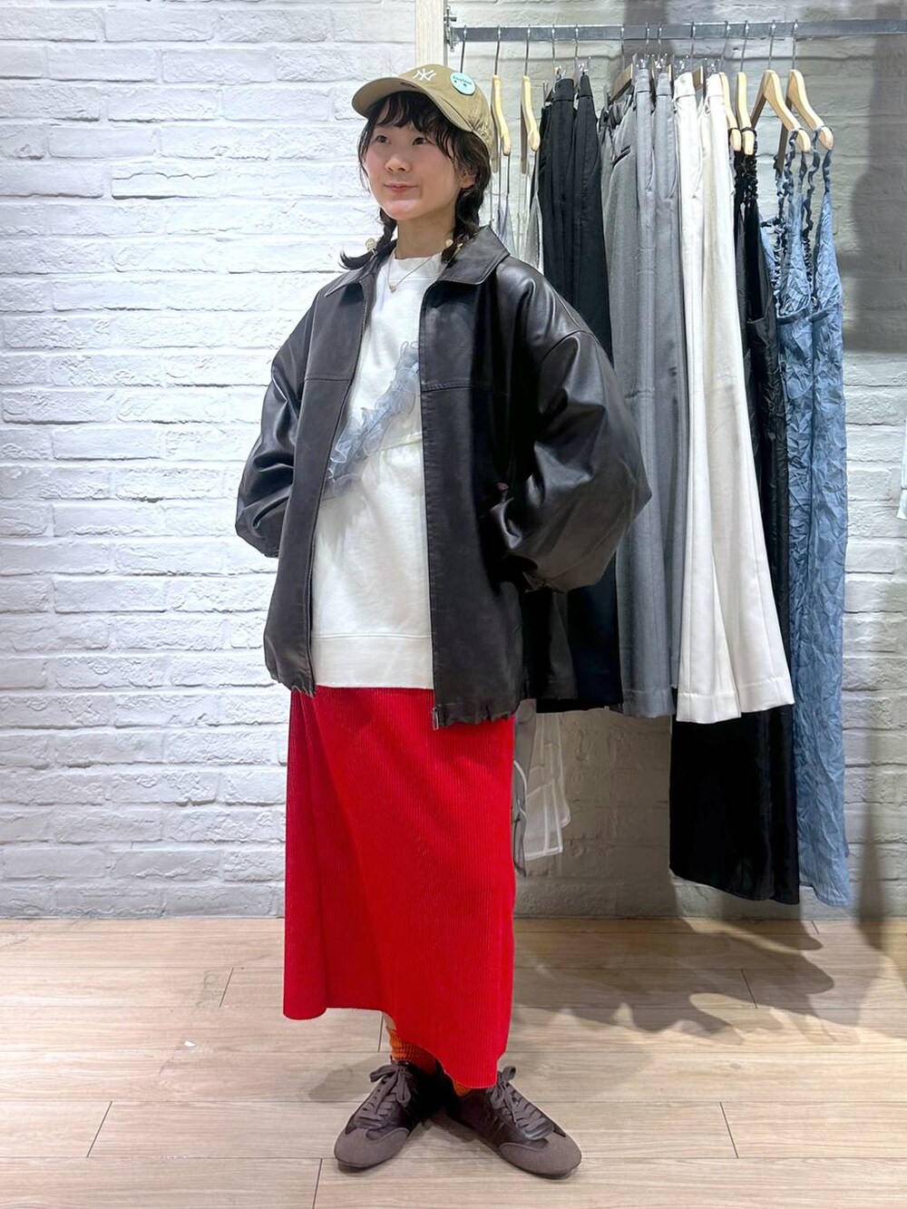 レッド系のスカート、ブラウン系のブルゾン、ホワイト系のスウェットを着用したレディースの春コーディネートの6枚目の写真