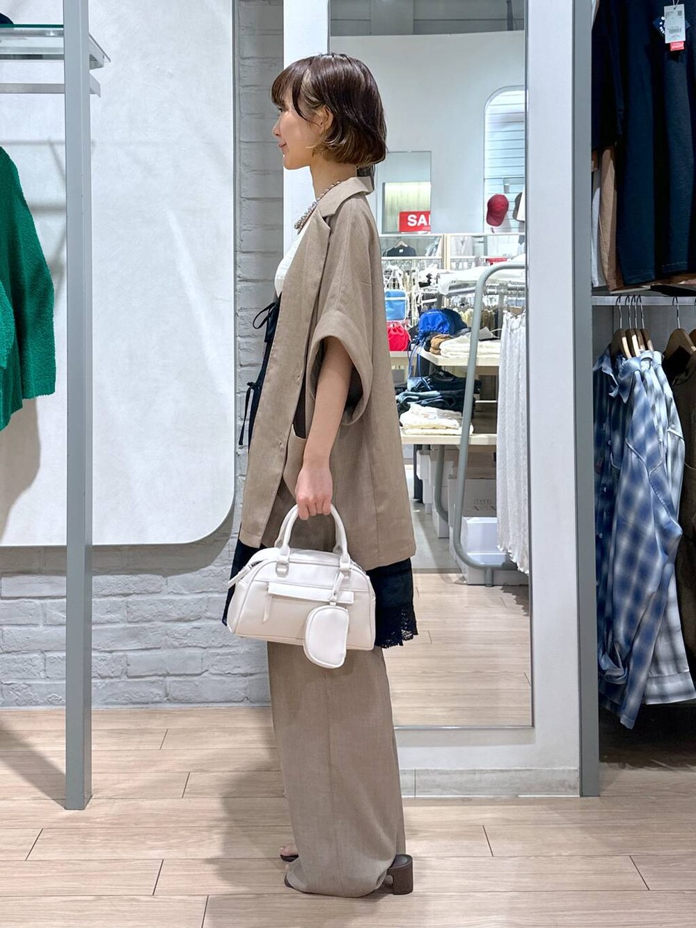 ホワイト系のタンクトップ、ブラウン系のサンダル、ベージュ系のテーラードジャケットを着用したレディースの夏コーディネートの5枚目の写真