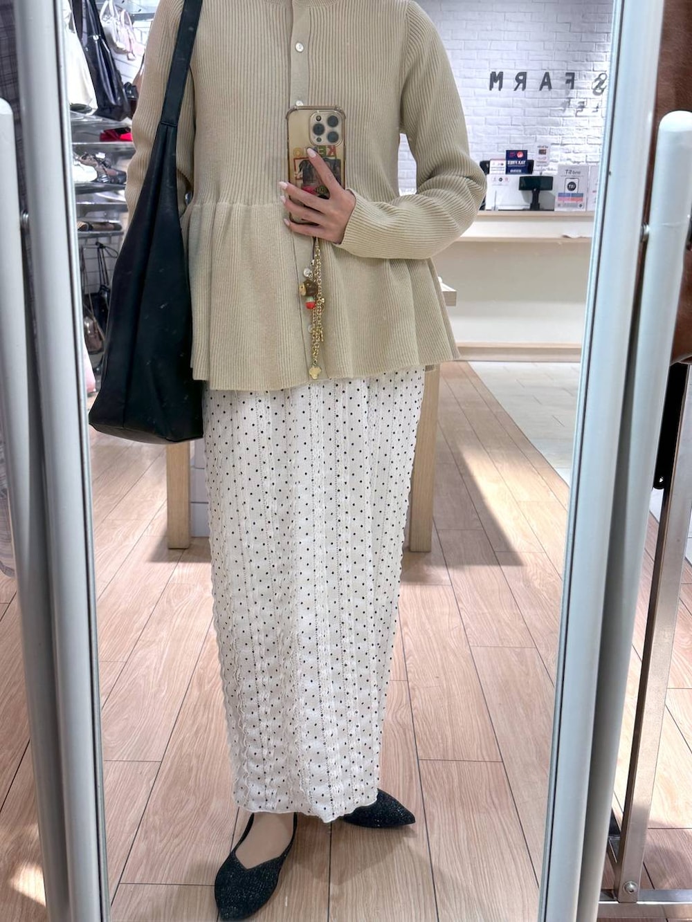 ブラック系のショルダーバッグ、ホワイト系のスカート、ホワイト系のカーディガン/ボレロを着用したレディースの春コーディネートの3枚目の写真