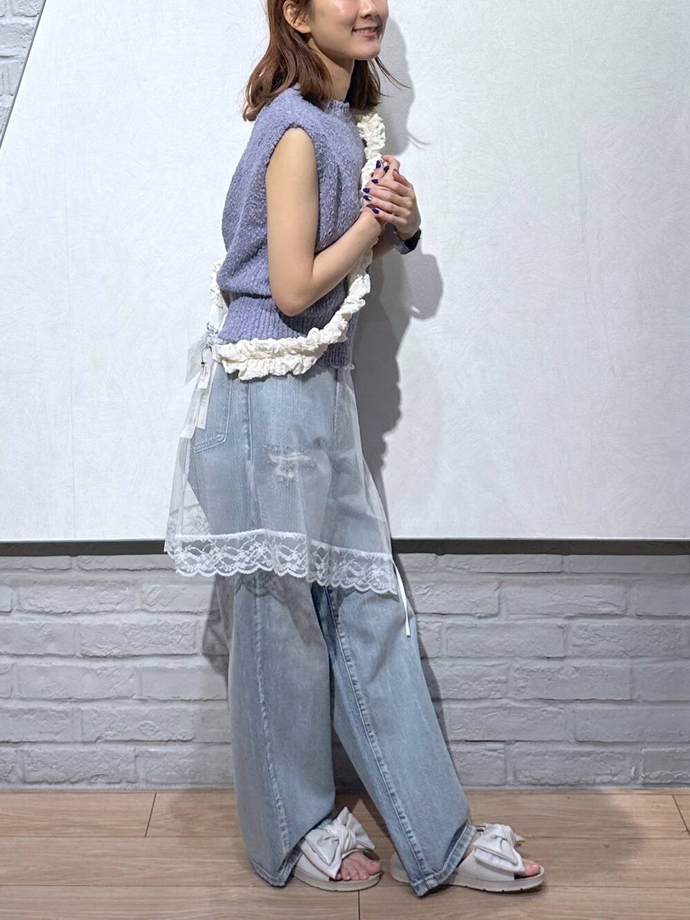 ホワイト系のサンダル、パープル系のベスト、ブルー系のデニムパンツを着用したレディースの夏コーディネートの6枚目の写真
