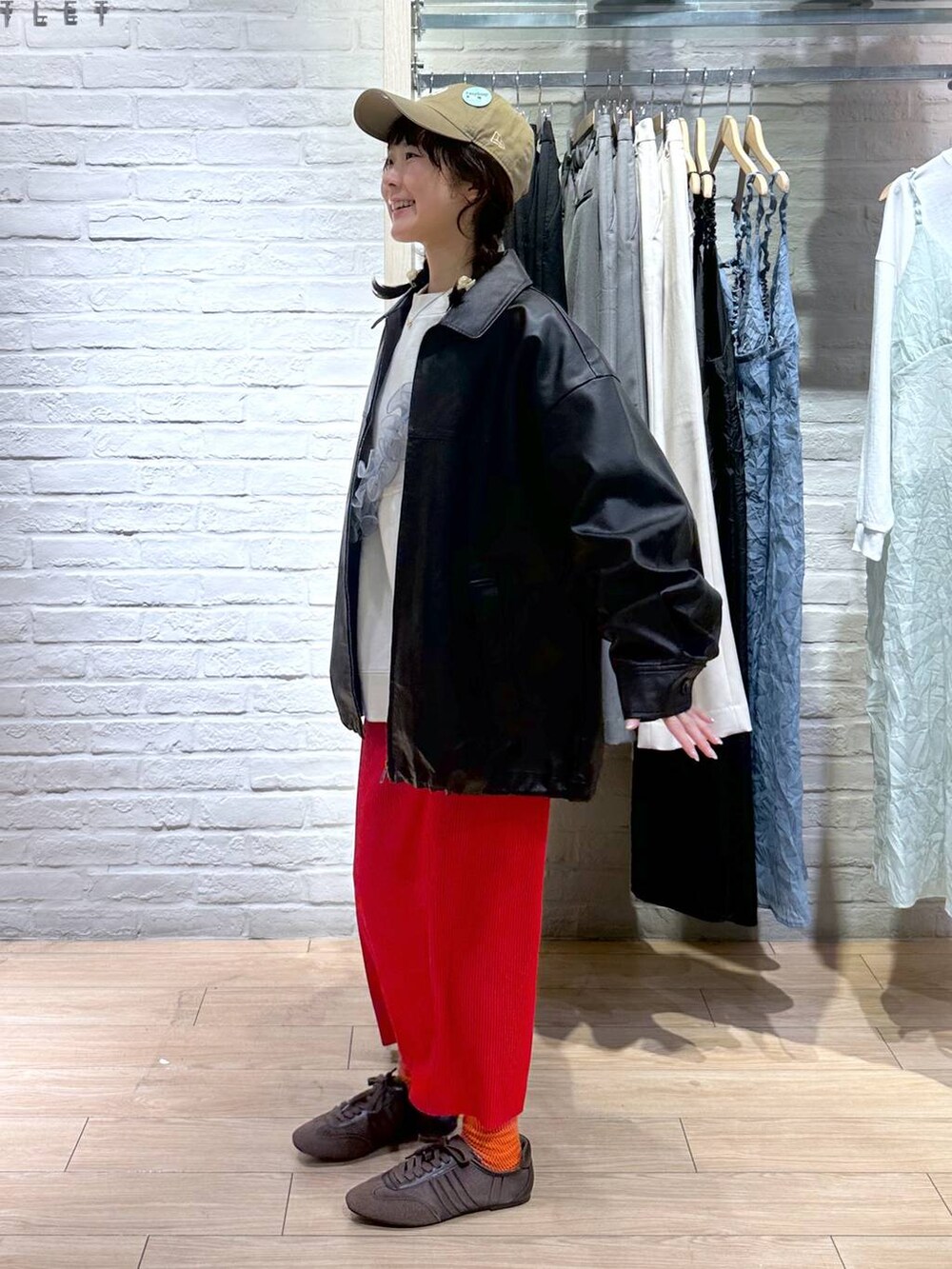 レッド系のスカート、ブラウン系のブルゾン、ホワイト系のスウェットを着用したレディースの春コーディネートの3枚目の写真