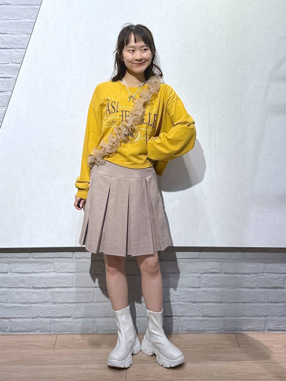 ホワイト系のブーツ、ベージュ系のスカート、イエロー系のTシャツ/カットソーを着用したレディースの秋コーディネートの5枚目の写真