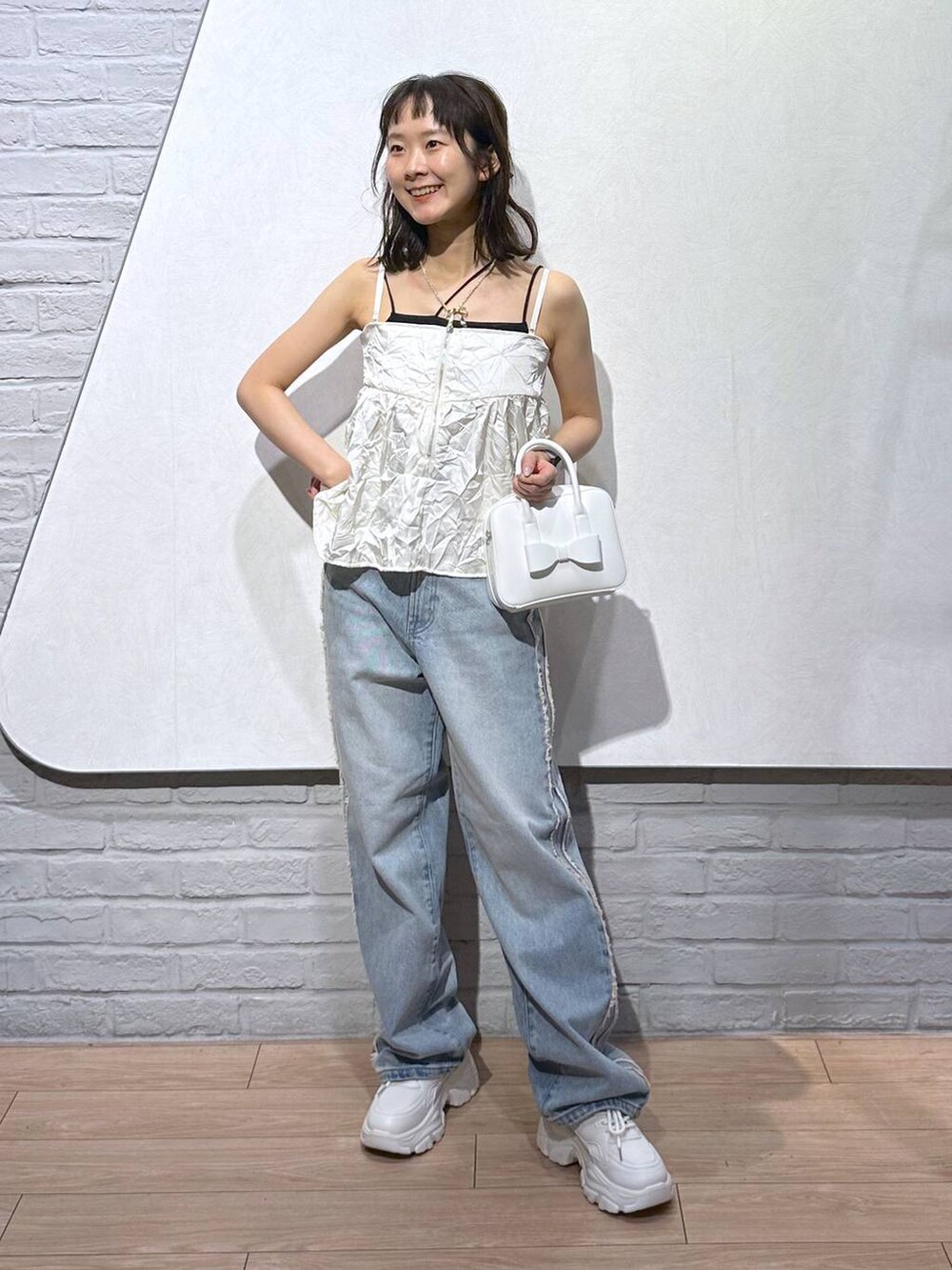 ホワイト系のスニーカー、ブラック系のキャミソール、ホワイト系のボストンバッグを着用したレディースの秋コーディネートの5枚目の写真