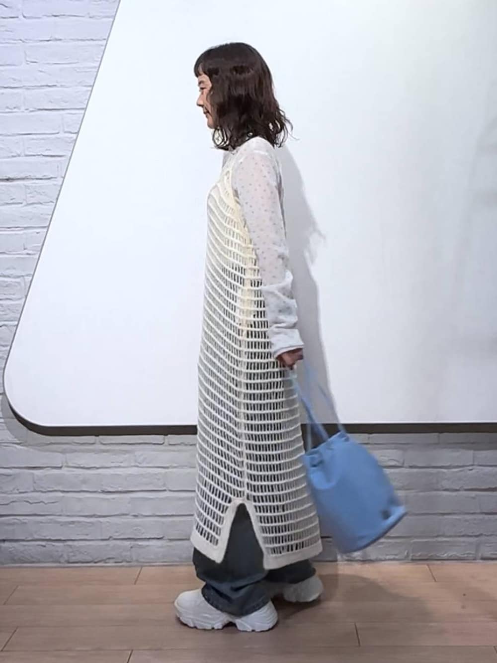 ブルー系のデニムパンツ、ホワイト系のワンピース、ブルー系のハンドバッグを着用したレディースの秋コーディネートの4枚目の写真