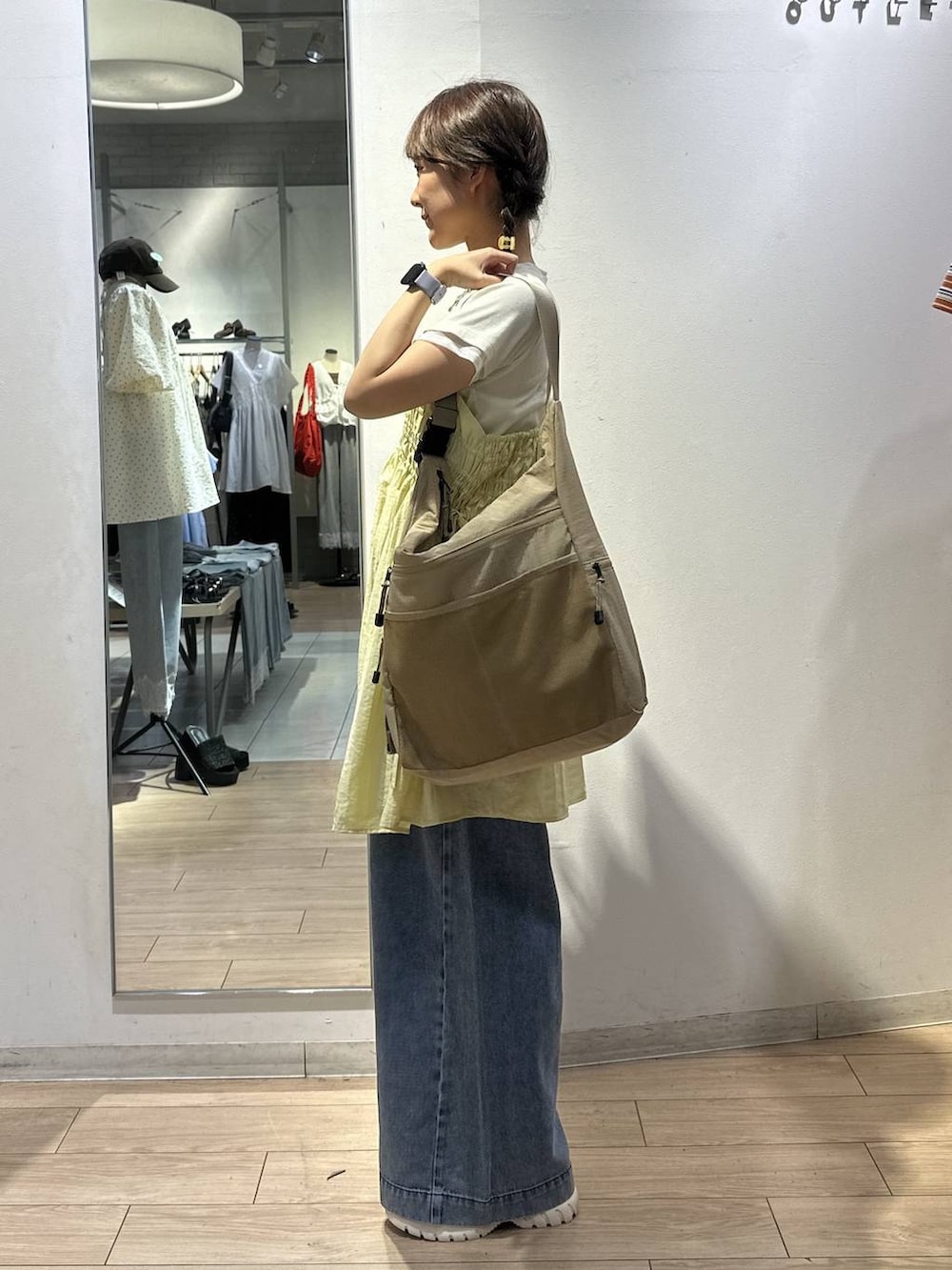 ベージュ系のショルダーバッグ、イエロー系のワンピース、ブルー系のデニムパンツを着用したレディースの夏コーディネートの2枚目の写真