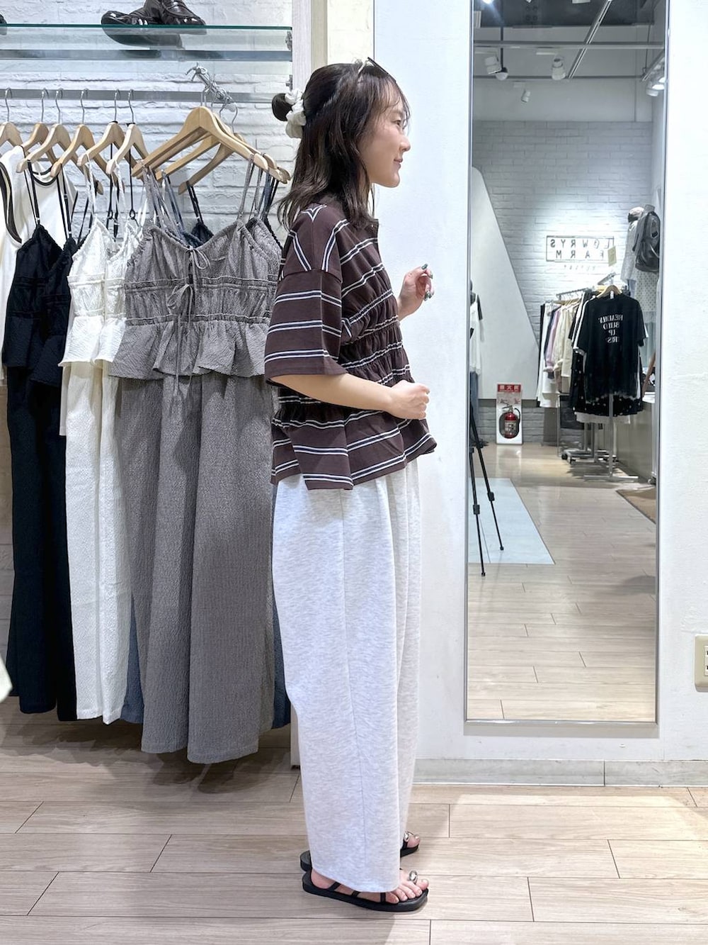 グレー系のスウェットパンツ、ホワイト系のショルダーバッグ、ブラック系のサンダルを着用したレディースの夏コーディネートの3枚目の写真