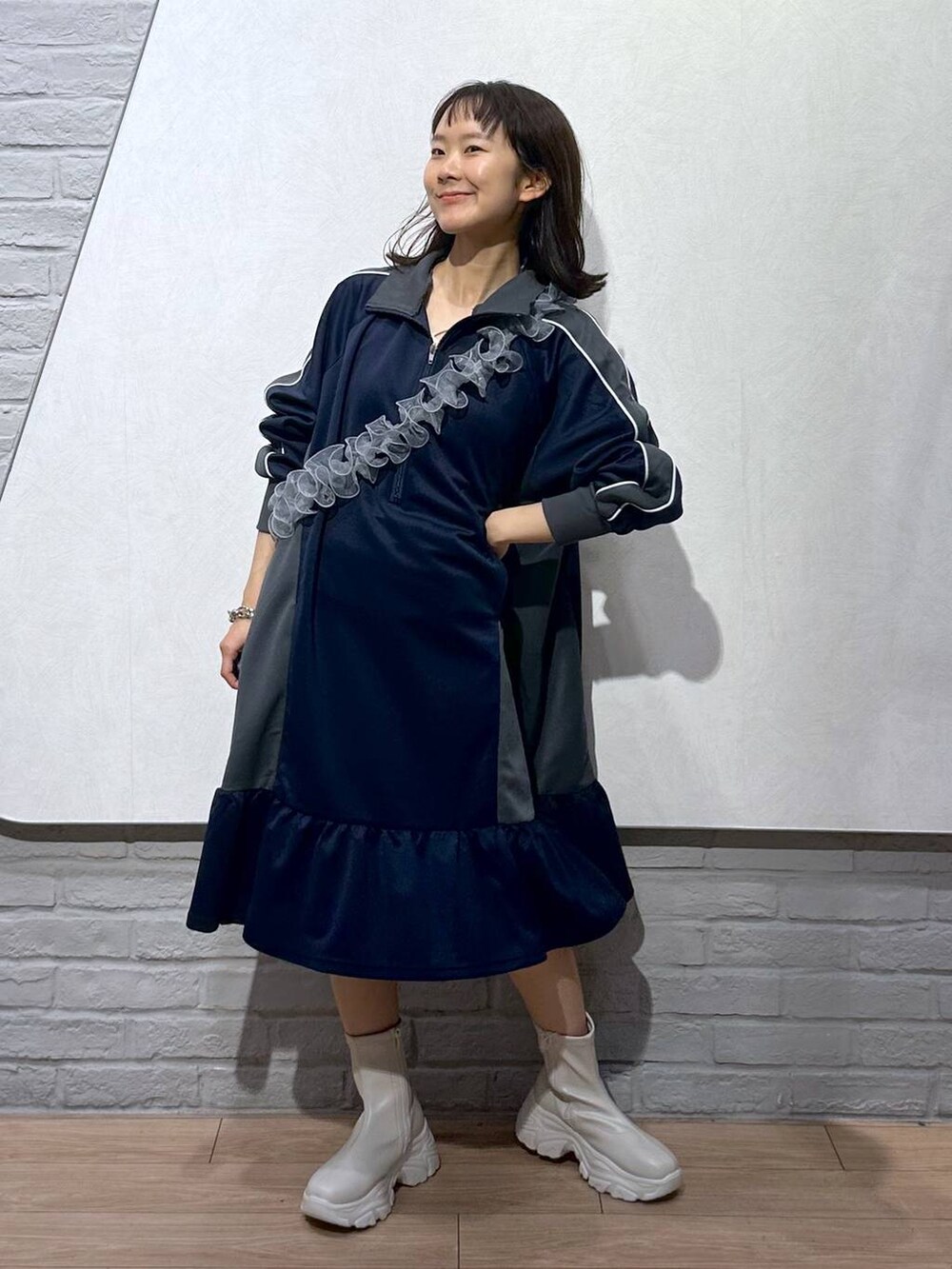 ホワイト系のブーツ、ブルー系のワンピース、グレー系のスマホグッズを着用したレディースの秋コーディネートの5枚目の写真