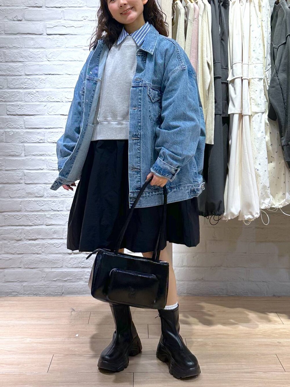 ブルー系のデニムジャケット、ブラック系のショルダーバッグ、ブラック系のブーツを着用したレディースの春コーディネートの3枚目の写真