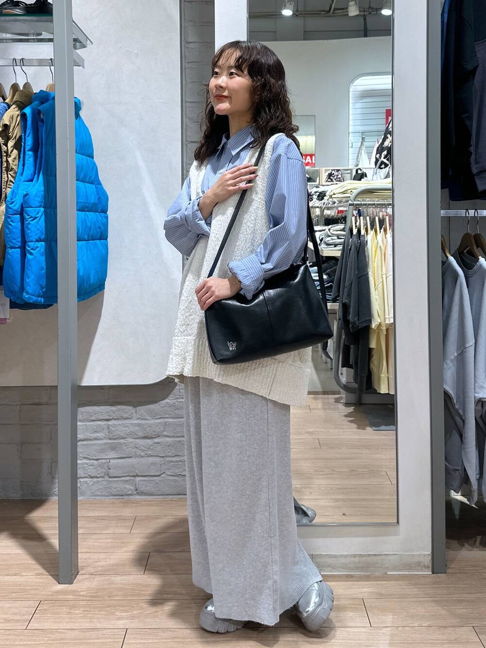 グレー系のスカート、ブルー系のシャツ/ブラウス、ホワイト系のニット/セーターを着用したレディースの春コーディネートの2枚目の写真