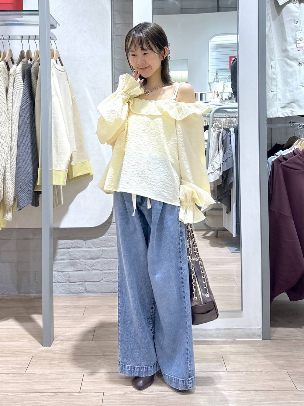 ブルー系のデニムパンツ、ブラウン系のショルダーバッグ、ブラウン系のサンダルを着用したレディースの春コーディネートの4枚目の写真