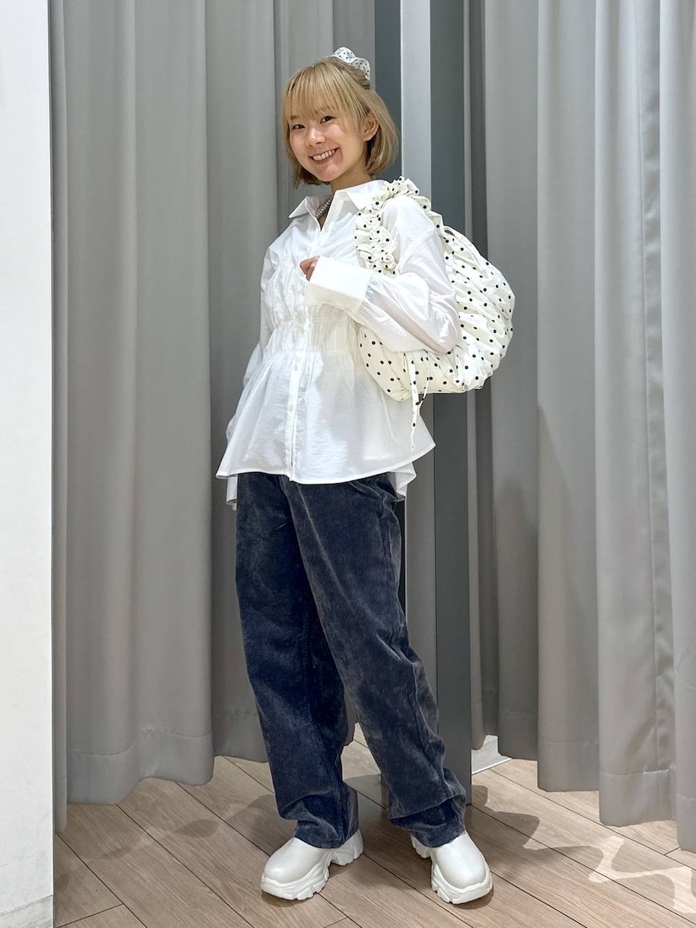 ホワイト系のブーツ、グレー系のデニムパンツ、ホワイト系のショルダーバッグを着用したレディースの秋コーディネートの4枚目の写真