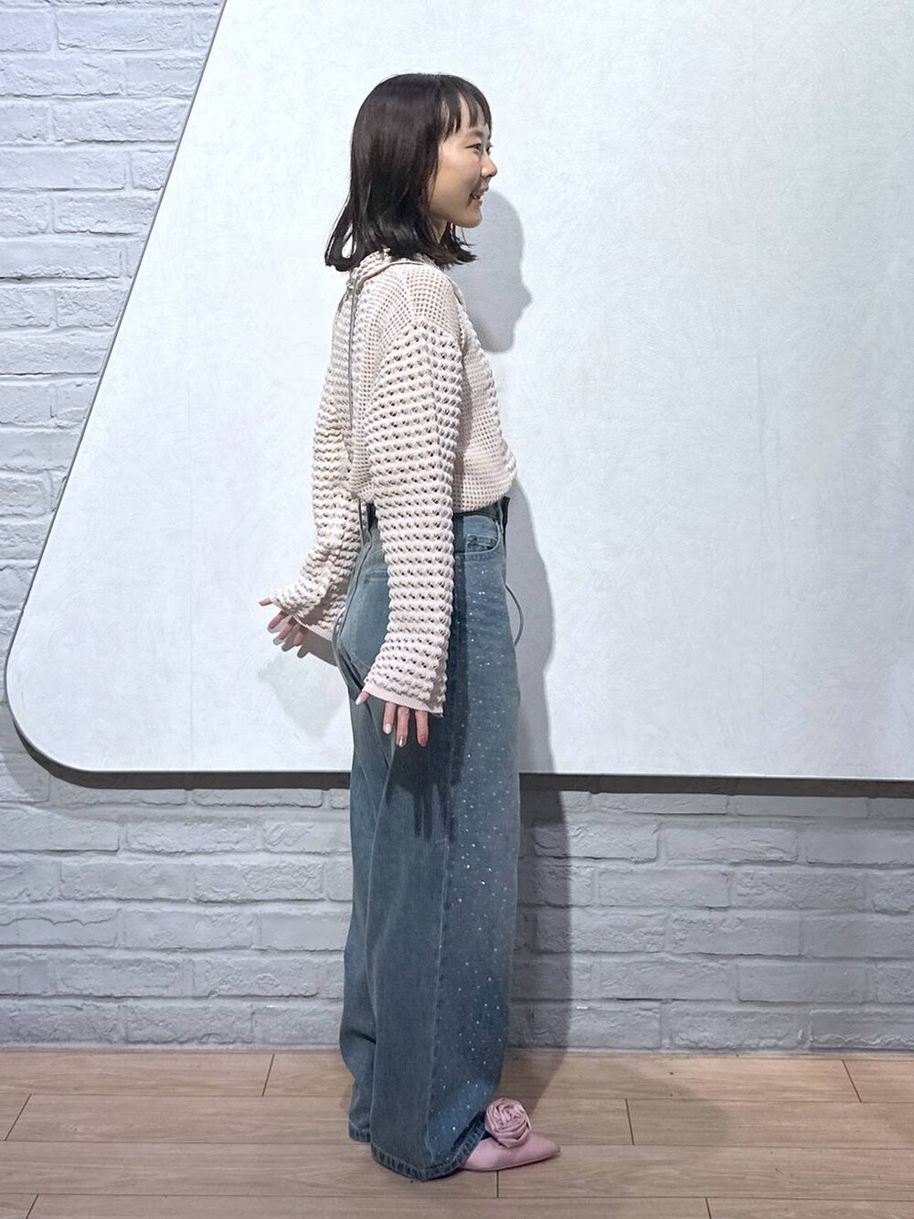 ピンク系のパンプス、シルバー系のショルダーバッグ、ブルー系のデニムパンツを着用したレディースの秋コーディネートの2枚目の写真