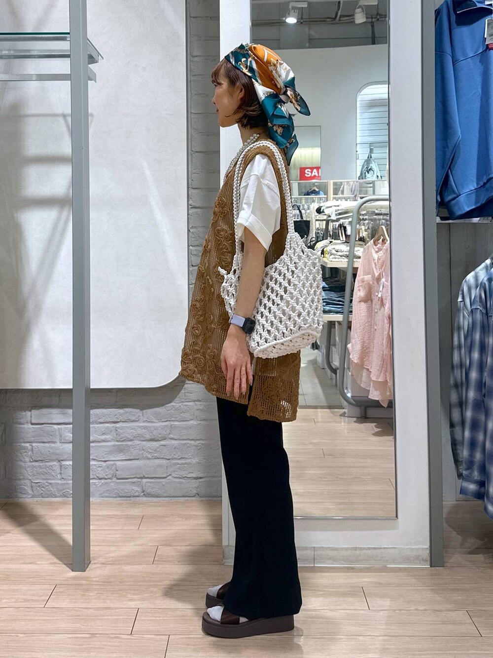 ブラウン系のサンダル、ホワイト系のトートバッグ、ホワイト系のTシャツ/カットソーを着用したレディースの夏コーディネートの2枚目の写真