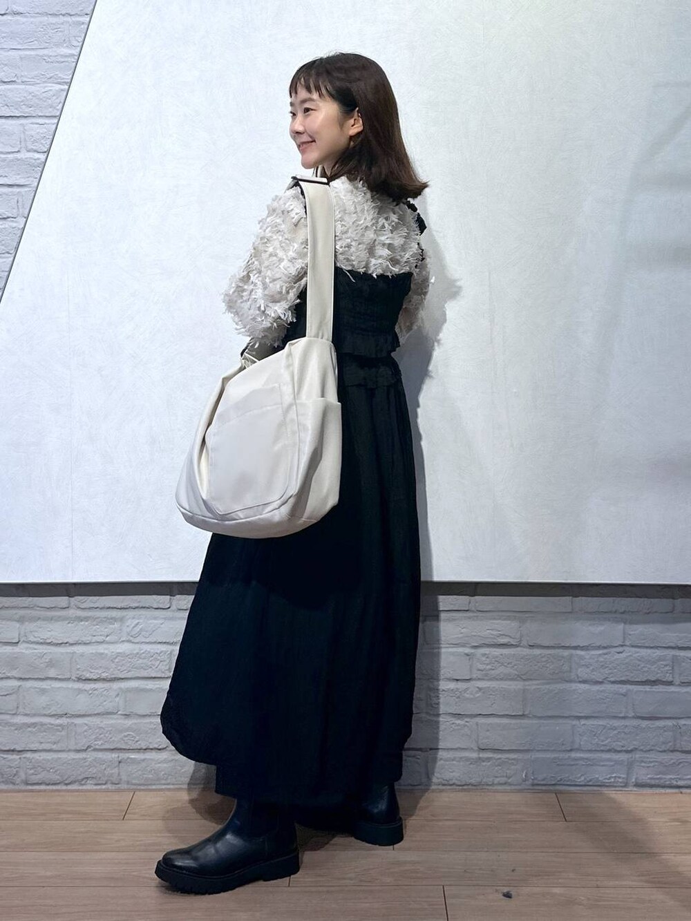 ホワイト系のボディバッグ/ウエストポーチ、ブラック系のワンピース、ホワイト系のニット/セーターを着用したレディースの秋コーディネートの2枚目の写真