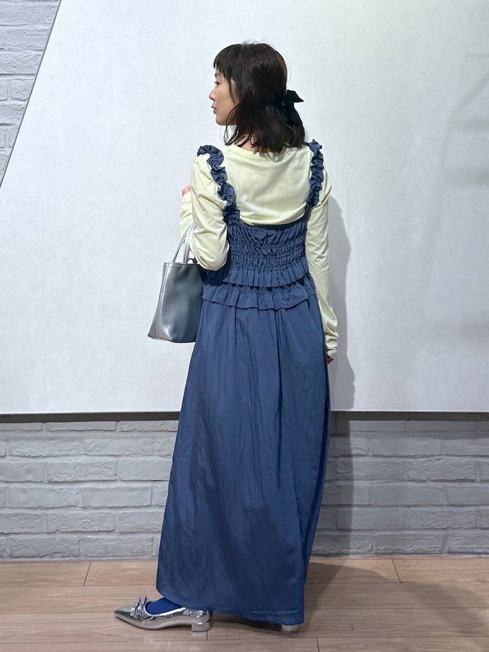 シルバー系のショルダーバッグ、シルバー系のパンプス、イエロー系のTシャツ/カットソーを着用したレディースの夏コーディネートの3枚目の写真