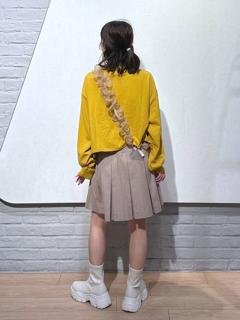 ホワイト系のブーツ、ベージュ系のスカート、イエロー系のTシャツ/カットソーを着用したレディースの秋コーディネートの3枚目の写真