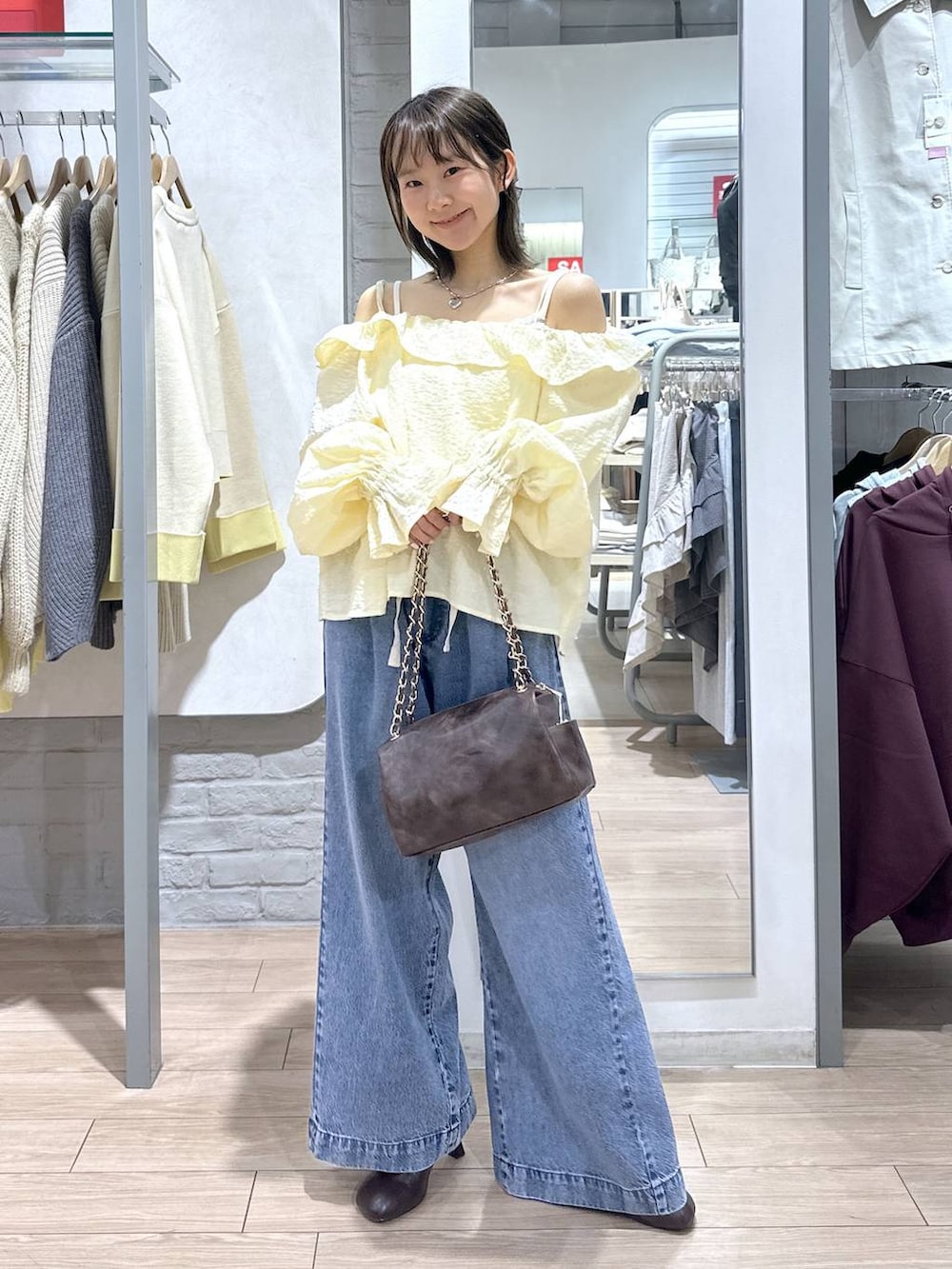 ブルー系のデニムパンツ、ブラウン系のショルダーバッグ、ブラウン系のサンダルを着用したレディースの春コーディネートの2枚目の写真