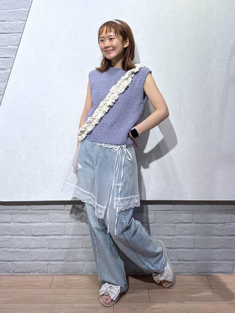 ホワイト系のサンダル、パープル系のベスト、ブルー系のデニムパンツを着用したレディースの夏コーディネートの3枚目の写真