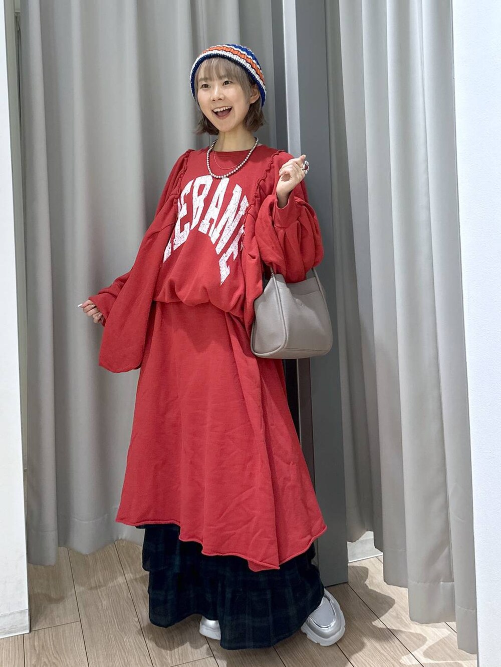 グレー系のショルダーバッグ、グリーン系のスカート、シルバー系のスニーカーを着用したレディースの秋コーディネートの2枚目の写真