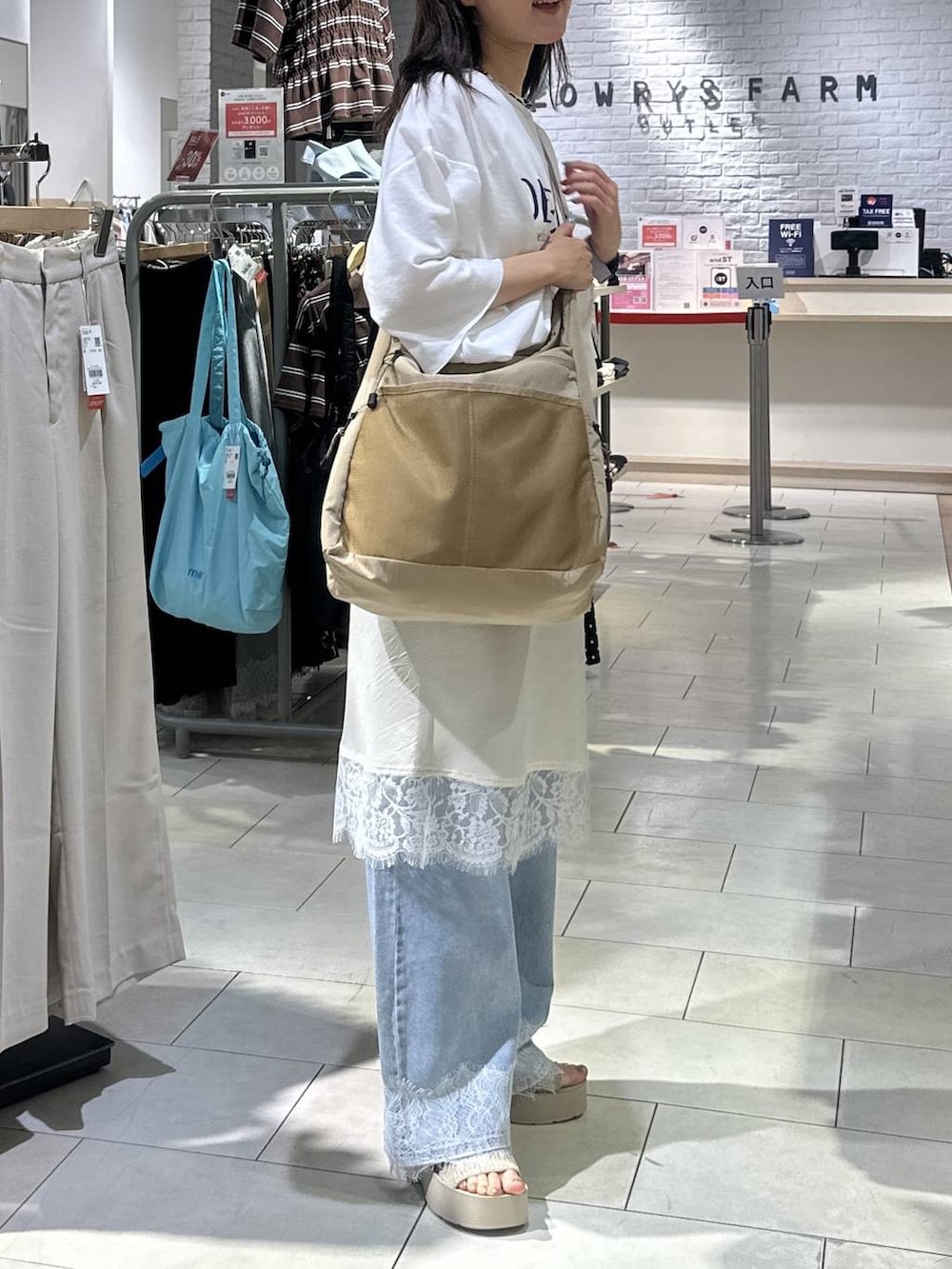ベージュ系のショルダーバッグ、ホワイト系のTシャツ/カットソー、ブルー系のデニムパンツを着用したレディースの夏コーディネートの3枚目の写真