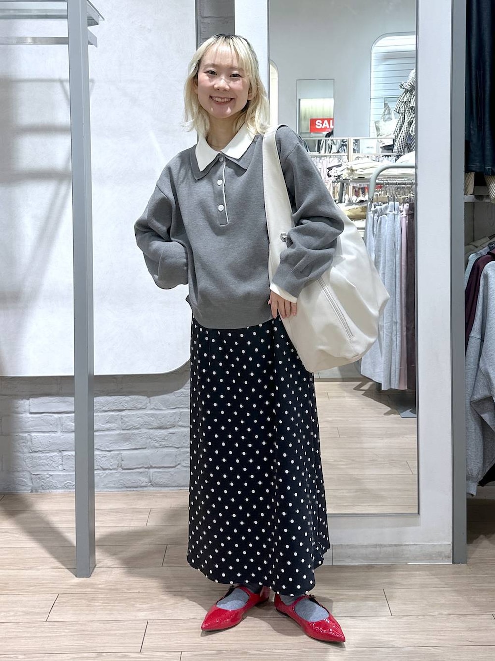 ブラック系のスカート、レッド系のパンプス、ホワイト系のショルダーバッグを着用したレディースの冬コーディネートの2枚目の写真