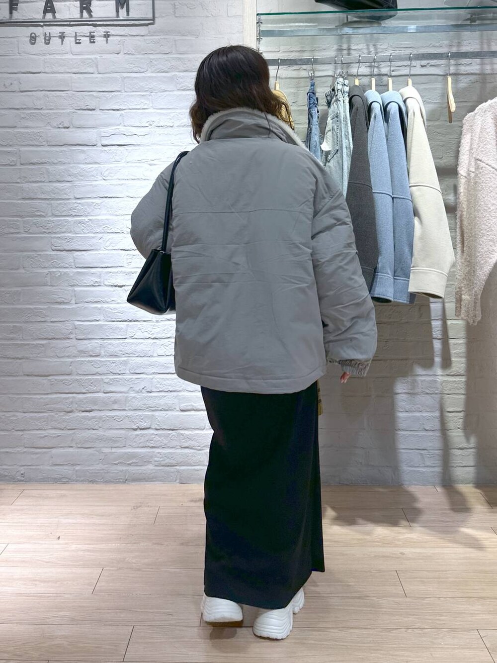 ブラック系のスカート、グリーン系のブルゾン、ベージュ系のスニーカーを着用したレディースの冬コーディネートの5枚目の写真