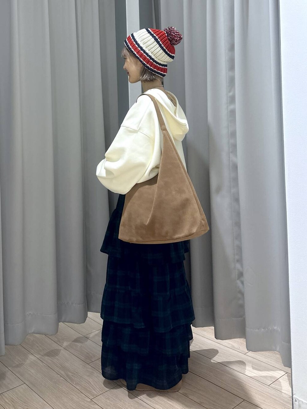 ベージュ系のショルダーバッグ、ブラウン系のスニーカー、グリーン系のスカートを着用したレディースの秋コーディネートの3枚目の写真