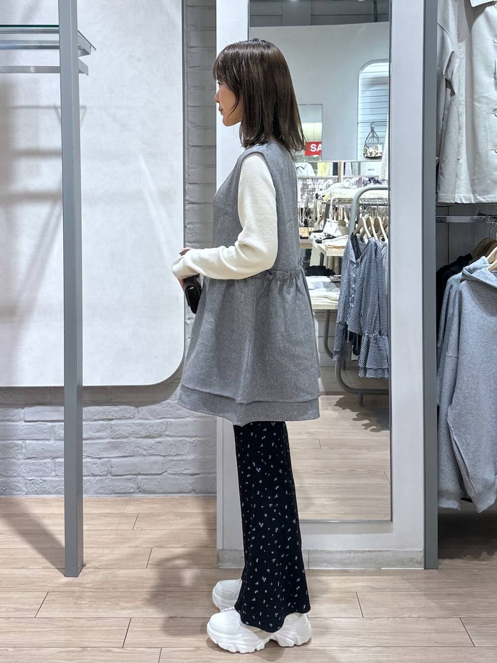 グレー系のベスト、ホワイト系のニット/セーター、ブラック系のボディバッグ/ウエストポーチを着用したレディースの春コーディネートの3枚目の写真