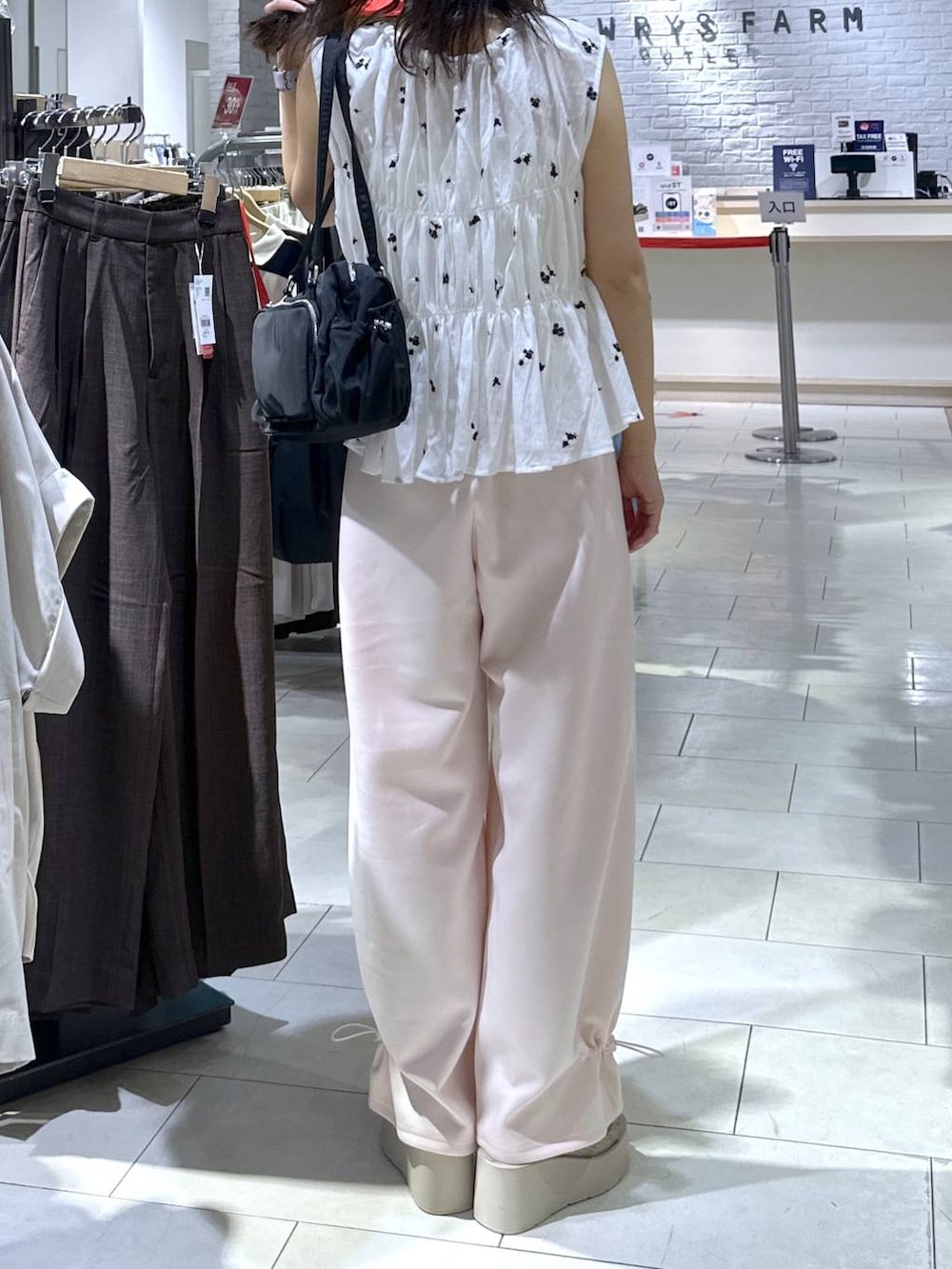 ピンク系のスウェットパンツ、ホワイト系のサンダル、ホワイト系のシャツ/ブラウスを着用したレディースの夏コーディネートの3枚目の写真