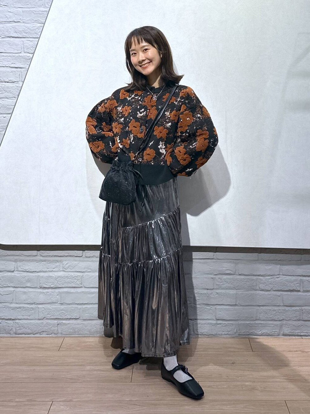 ブラック系のショルダーバッグ、グレー系のスカート、ブラック系のバレエシューズを着用したレディースの秋コーディネートの2枚目の写真