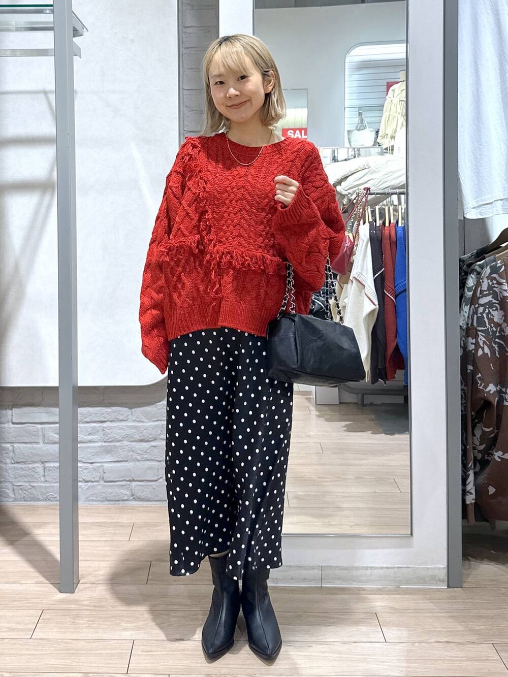 ブラック系のスカート、レッド系のポロシャツ、ブラック系のブーツを着用したレディースの冬コーディネートの4枚目の写真