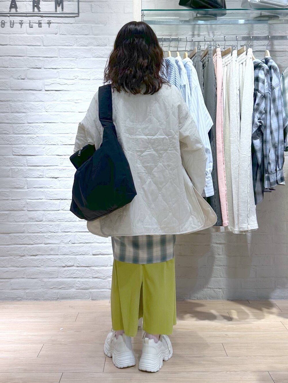 イエロー系のスカート、ホワイト系のブルゾン、ホワイト系のTシャツ/カットソーを着用したレディースの冬コーディネートの5枚目の写真