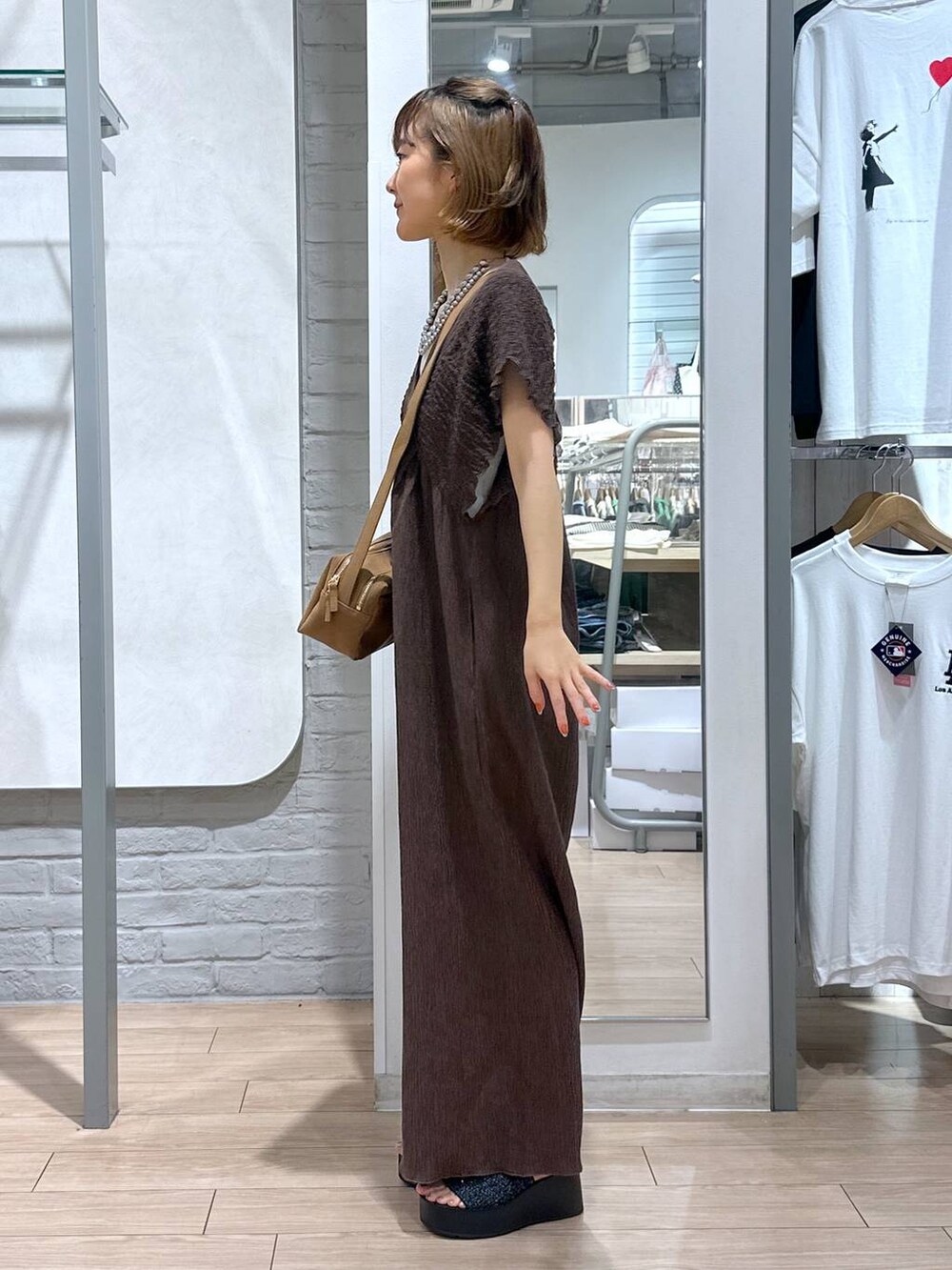 ホワイト系のTシャツ/カットソー、ブラック系のサンダル、ブラウン系のサロペット/オーバーオールを着用したレディースの夏コーディネートの3枚目の写真