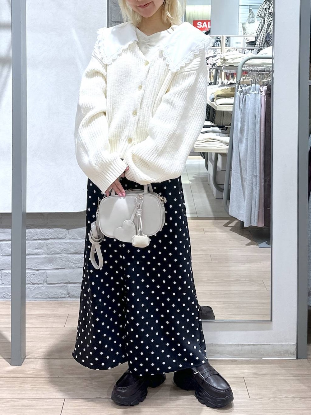 ブラック系のスカート、ホワイト系のボストンバッグ、ブラウン系のローファーを着用したレディースの冬コーディネートの2枚目の写真