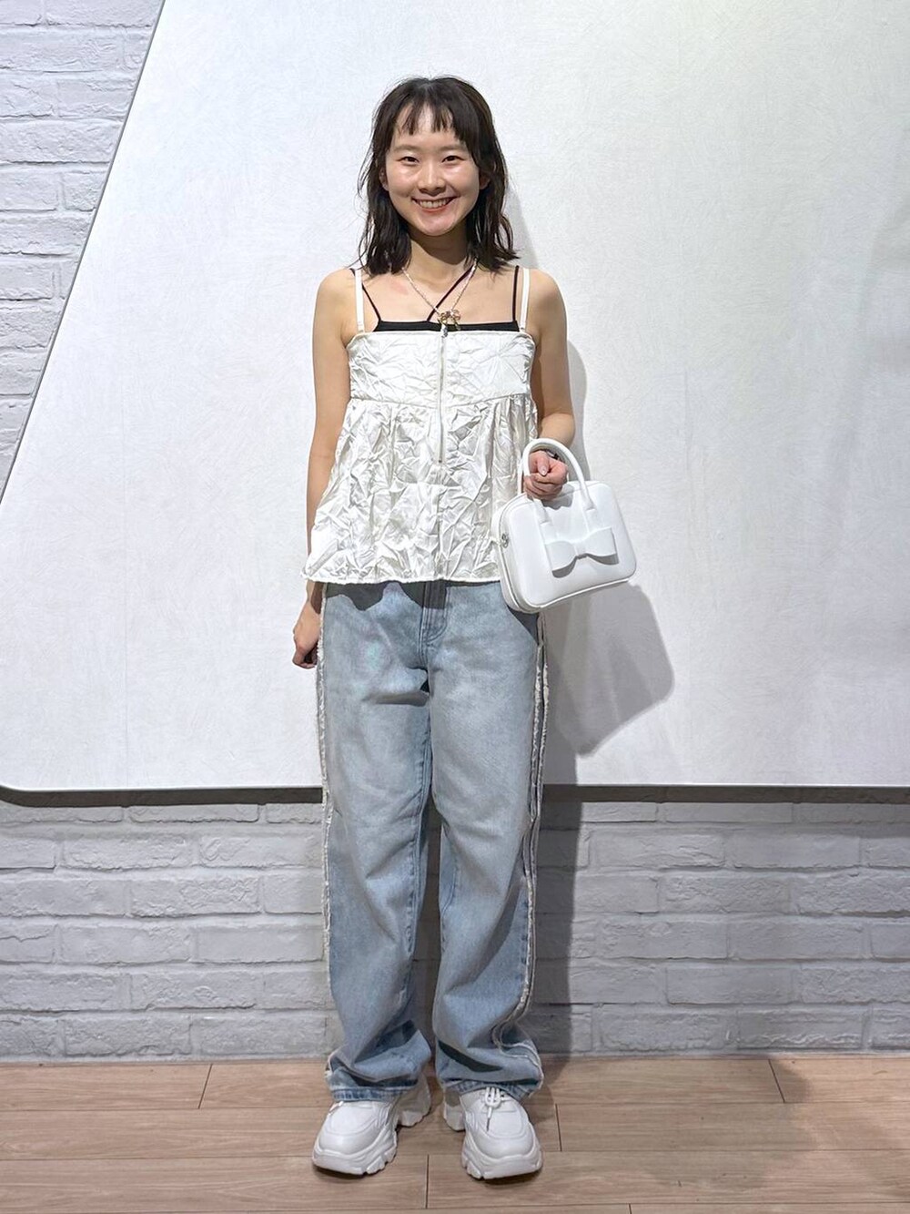 ホワイト系のスニーカー、ブラック系のキャミソール、ホワイト系のボストンバッグを着用したレディースの秋コーディネートの2枚目の写真