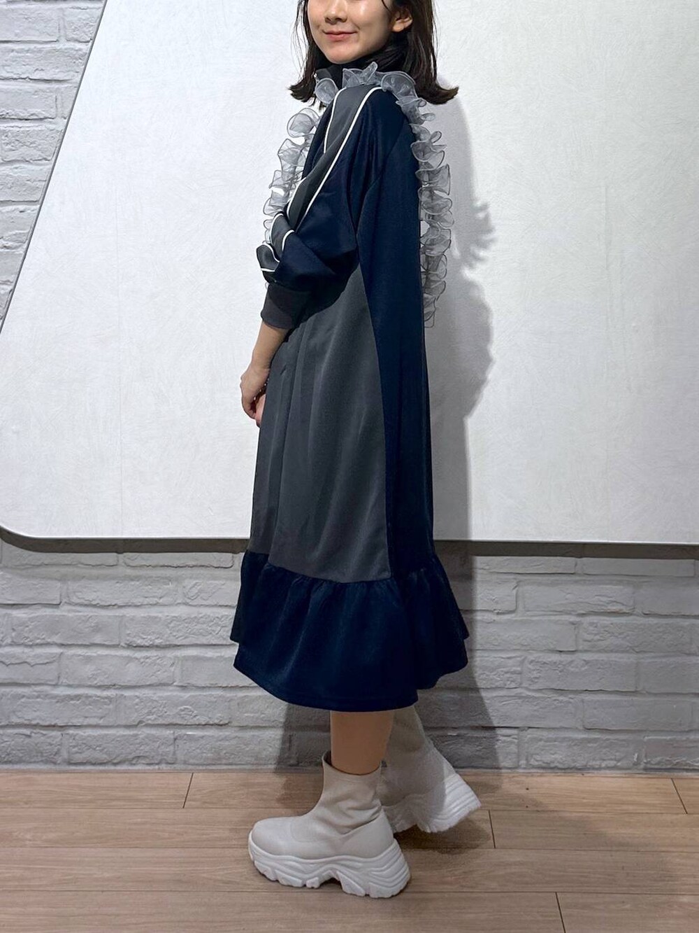 ホワイト系のブーツ、ブルー系のワンピース、グレー系のスマホグッズを着用したレディースの秋コーディネートの2枚目の写真