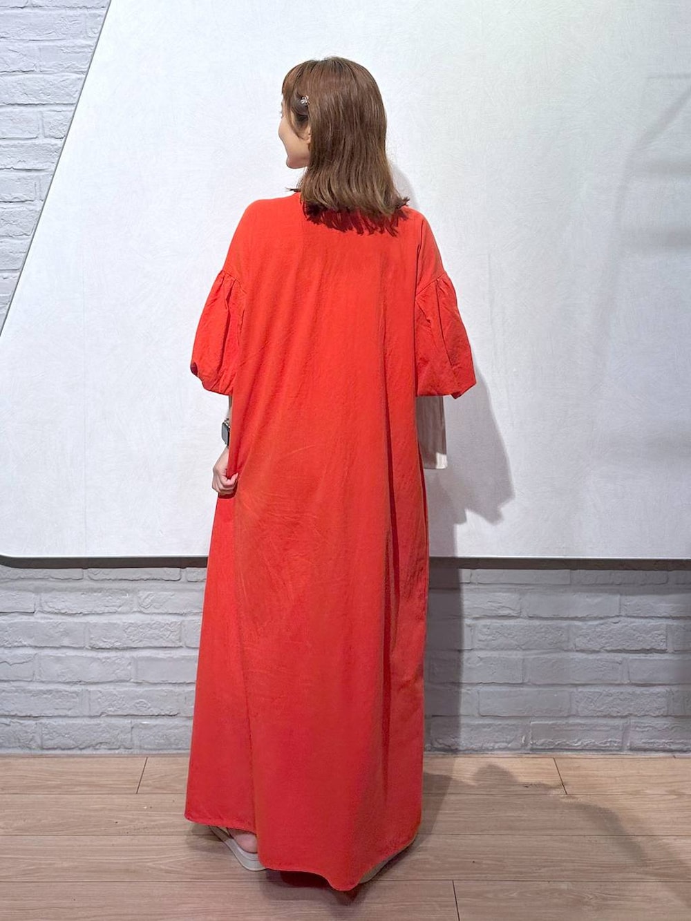 オレンジ系のワンピース、ホワイト系のトートバッグ、ホワイト系のサンダルを着用したレディースの夏コーディネートの4枚目の写真