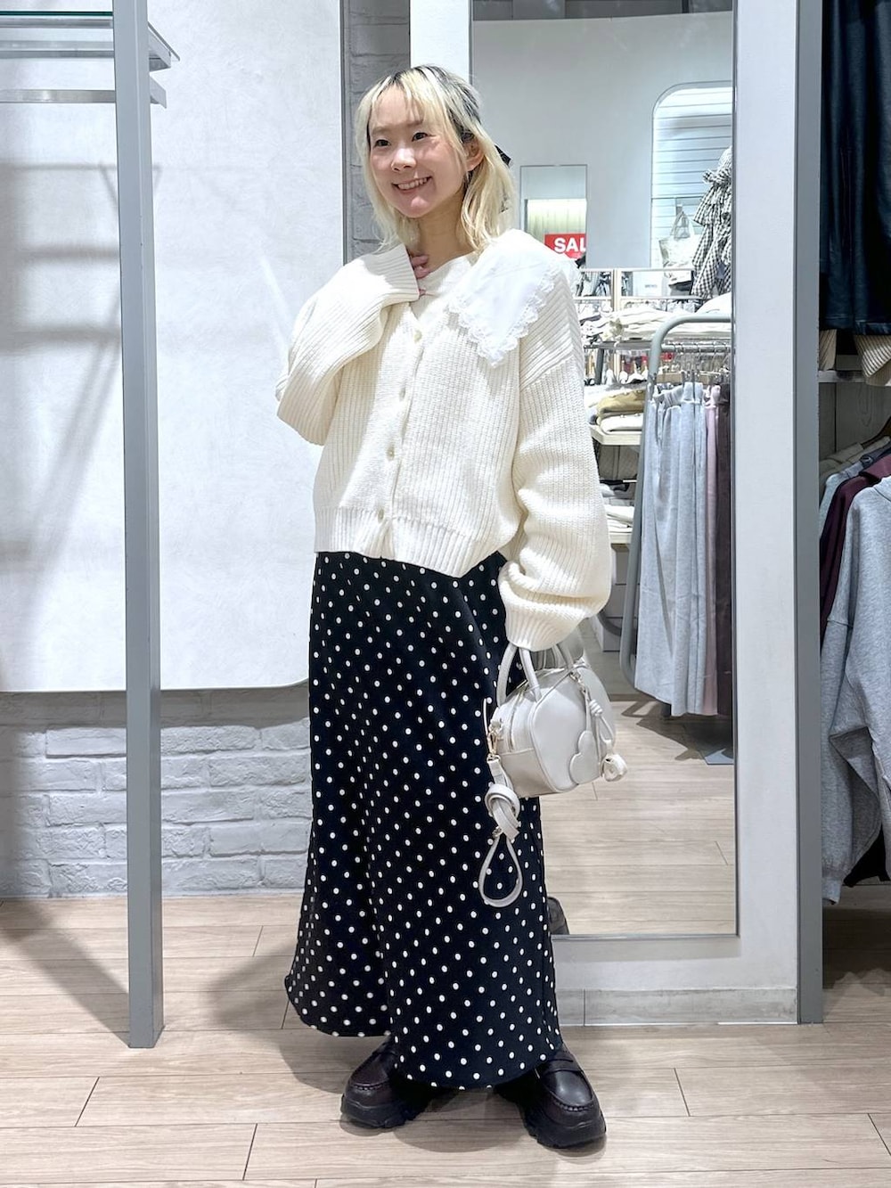 ブラック系のスカート、ホワイト系のボストンバッグ、ブラウン系のローファーを着用したレディースの冬コーディネートの4枚目の写真