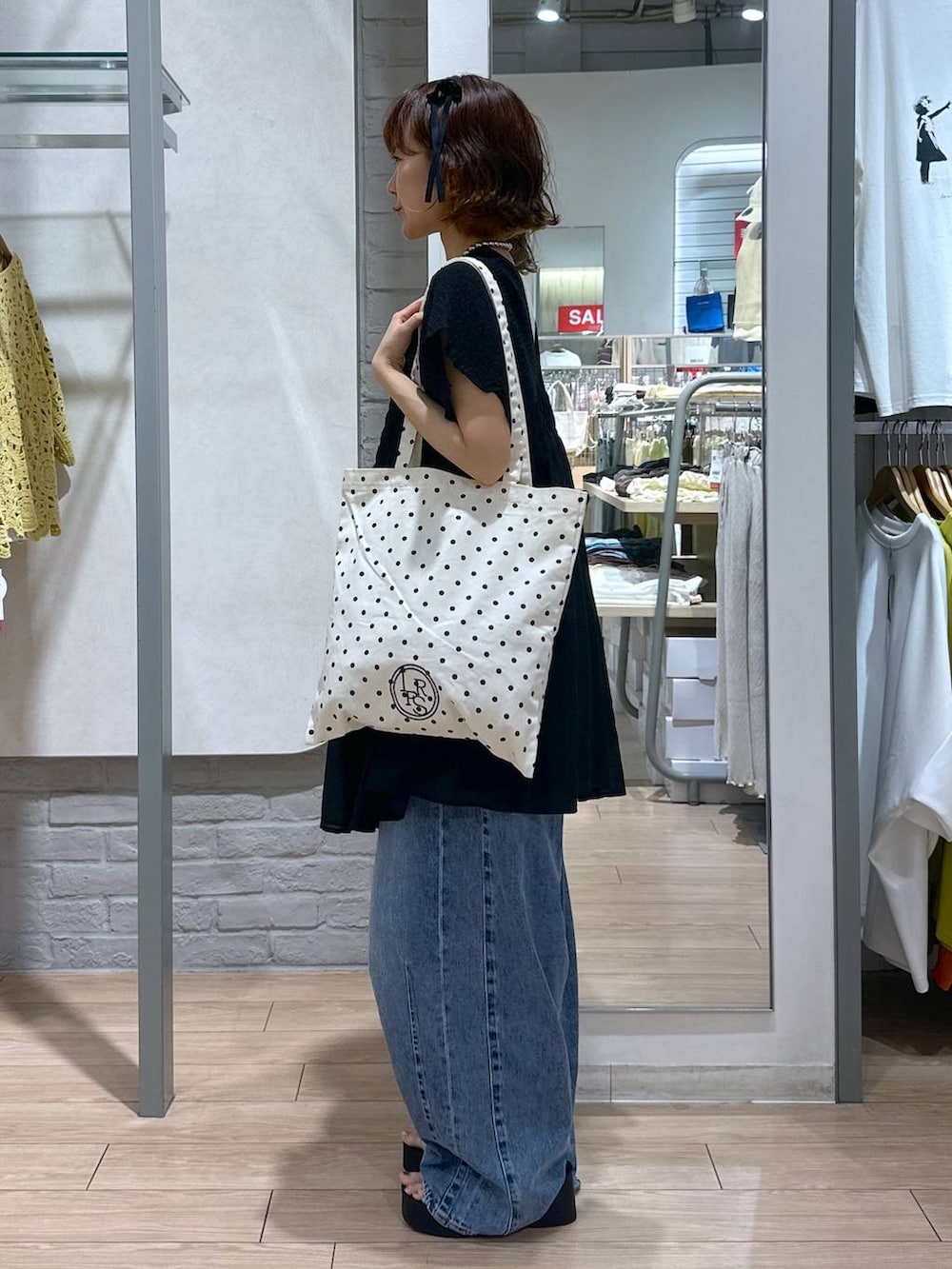 シルバー系のサンダル、その他のトートバッグ、ブルー系のデニムパンツを着用したレディースの夏コーディネートの2枚目の写真