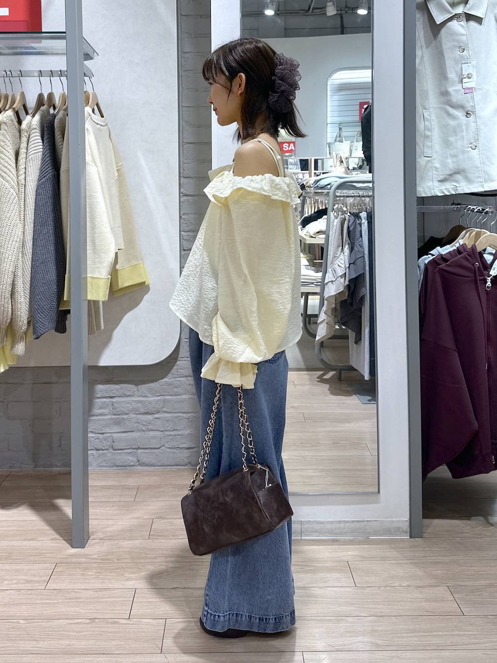 ブルー系のデニムパンツ、ブラウン系のショルダーバッグ、ブラウン系のサンダルを着用したレディースの春コーディネートの3枚目の写真