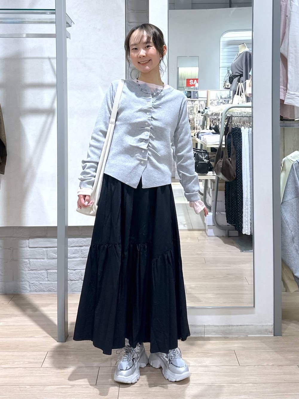 ホワイト系のショルダーバッグ、ピンク系のTシャツ/カットソー、ブラック系のスカートを着用したレディースの春コーディネートの2枚目の写真